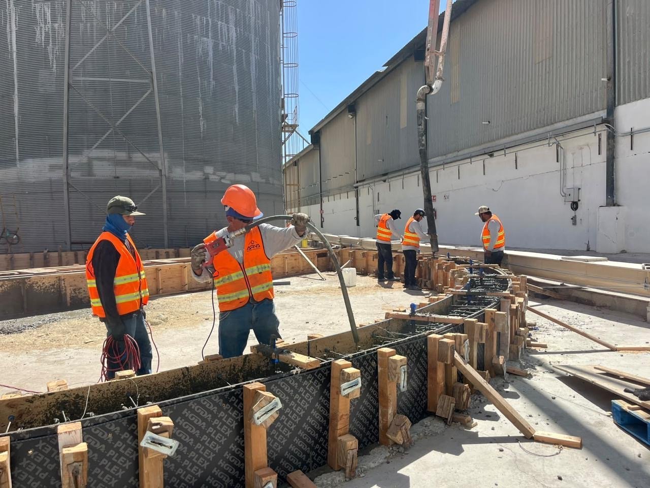 Personal de obra trabajando en cimbra junto a silos