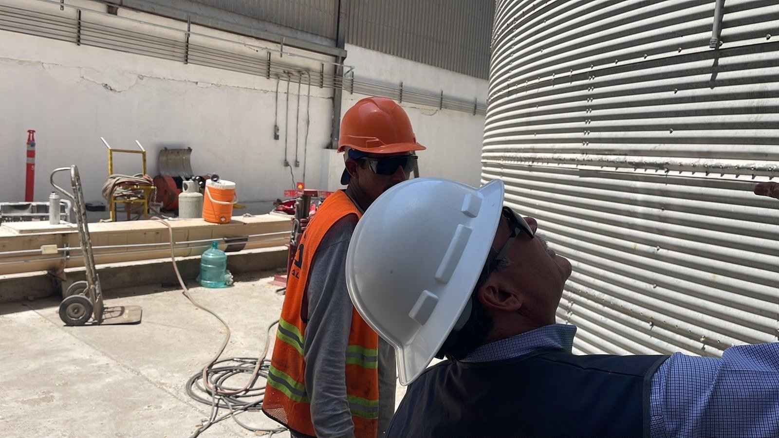 Dos personas con casco junto a un silo durante una visita de obra