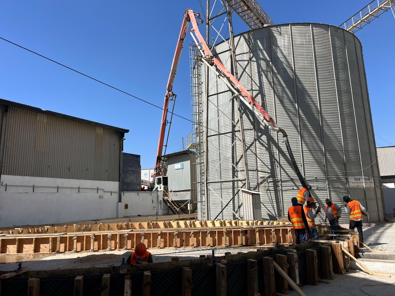Personal, cimbra y equipo de colocación de concreto junto a silos